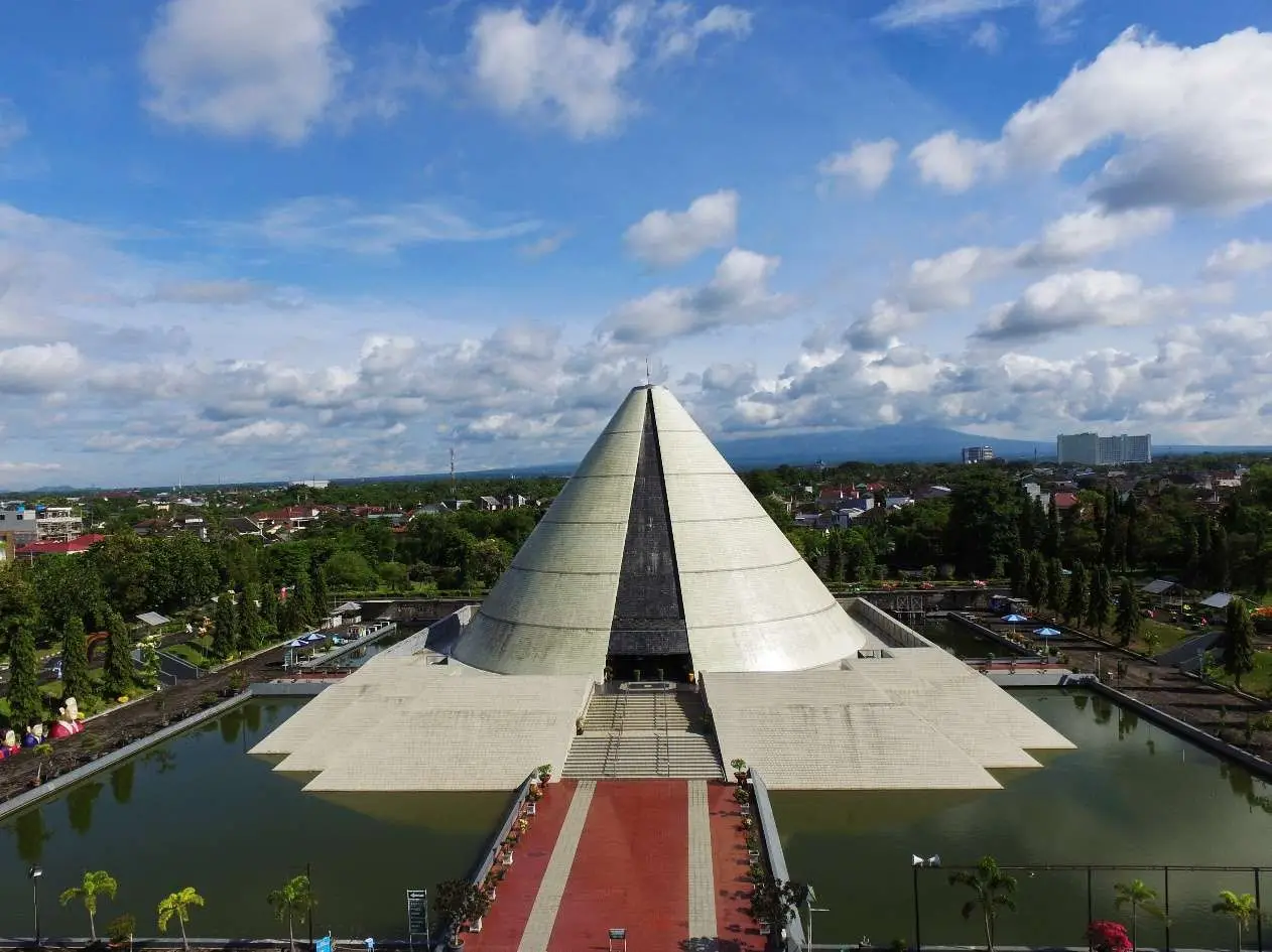Foto Monumen Jogja Kembali (Monjali) Yogyakarta dengan arsitektur unik berbentuk kerucut dan suasana taman di sekitarnya